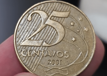 Close macro da face de uma moeda de 25 centavos de 2001, focando no numeral e no ano de fabricação, segurada por dedos em detalhe.
