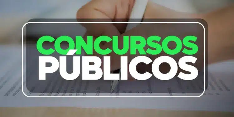 Mão segurando caneta preenchendo gabarito de prova de concurso público com questões objetivas.