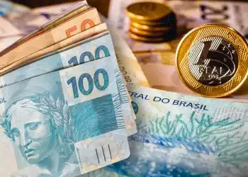 Dinheiro brasileiro com notas de 50 e 100 reais e moedas de real sobre superfície