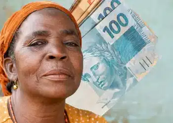 Mulher negra com lenço laranja na cabeça segurando várias cédulas de 100 reais brasileiras