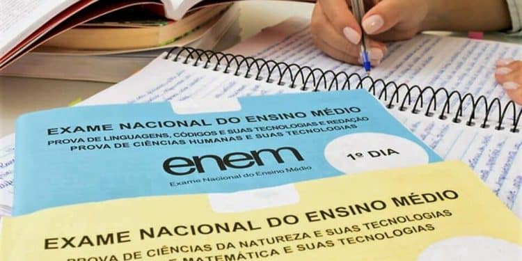 Cadernos de prova do Enem com material de estudo e mão escrevendo.