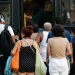 Pessoas de diferentes idades esperando e entrando em ônibus público em ambiente urbano