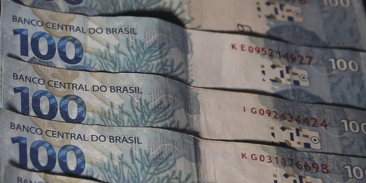 Pessoa segurando notas de 100 reais frente.