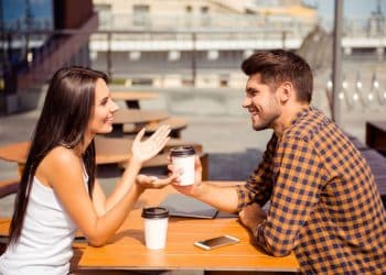 Homem e mulher conversam em uma cafeteria ao ar livre, representando comunicação em espanhol.