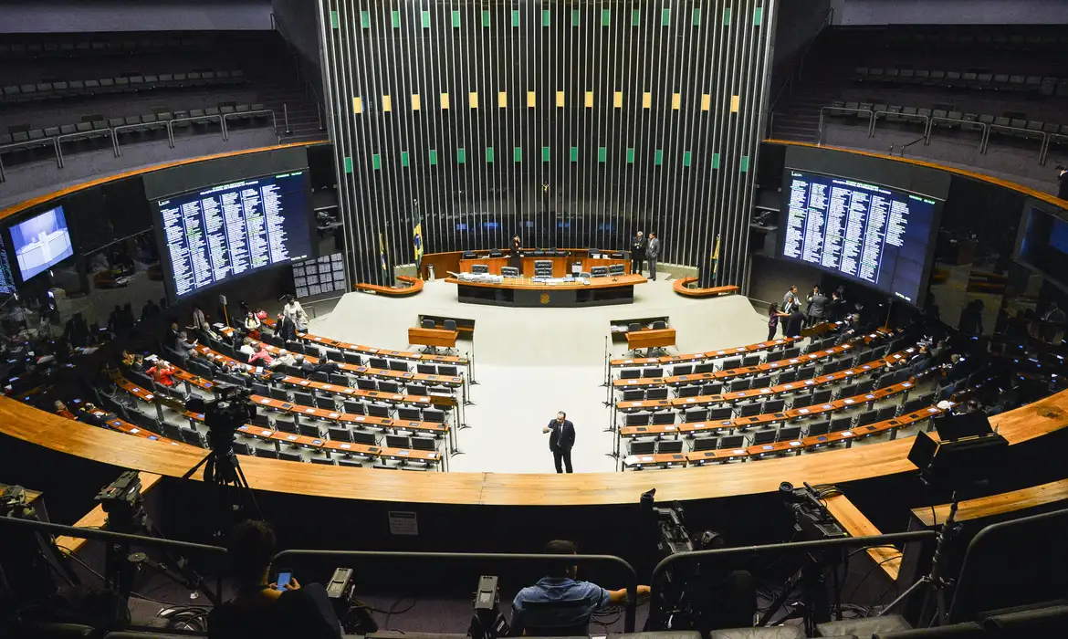 Plenário da Câmara dos Deputados vazio com detalhes da votação Vista panorâmica do plenário da Câmara dos Deputados com cadeiras, mesas e telões de votação eletrônica