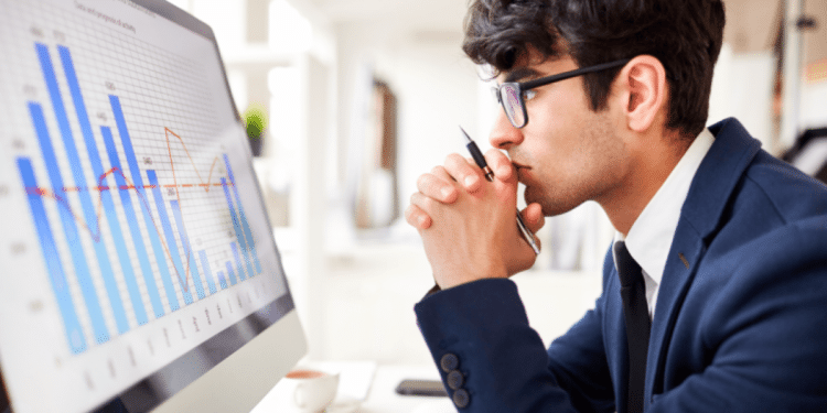 Profissional analisa gráficos de desempenho e dados estratégicos em ambiente corporativo de tecnologia.