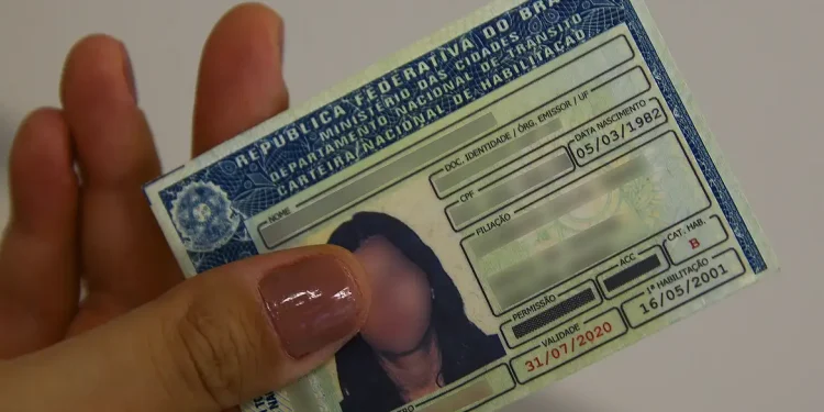Aulas Teóricas CNH Agora Remotas Sem Autoescola Mão segurando a Carteira Nacional de Habilitação (CNH) no novo modelo. A imagem representa a flexibilização das regras de obtenção, permitindo que as aulas teóricas sejam feitas de forma remota.