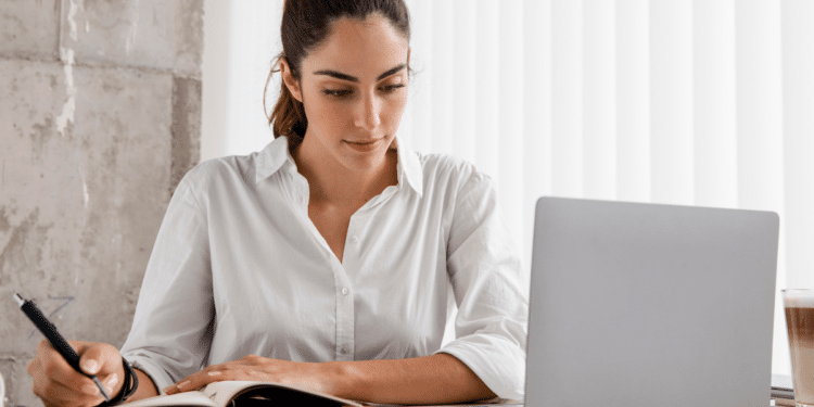 Candidata estudando para concursos públicos com material de preparação e computador em ambiente de estudo.