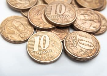 Close-up de moedas de 10 centavos do Real, incluindo o ano de 2008, destacando a raridade por defeitos de cunhagem. A imagem ilustra a busca por peças valiosas para colecionadores.