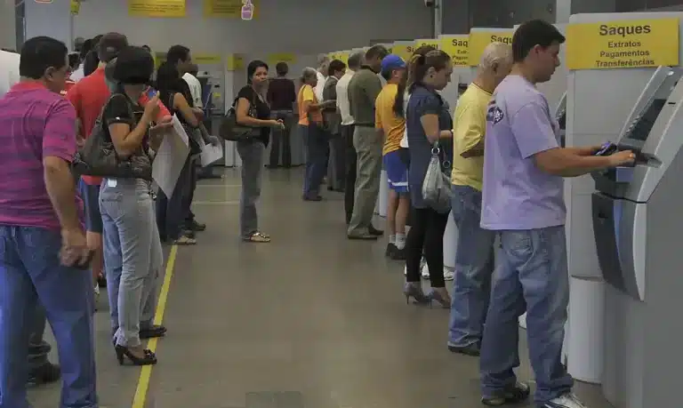 Fila em bancos para uso de caixas eletrônicos Pessoas em fila aguardando para usar caixas eletrônicos em banco
