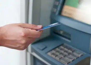 Cliente utilizando caixa eletrônico enquanto verifica informações sobre o funcionamento da CAIXA e do Banco do Brasil no dia 24 de dezembro.