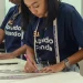 Jovem mulher trabalhando com régua e lápis em mesa, vestindo camiseta azul do Senai