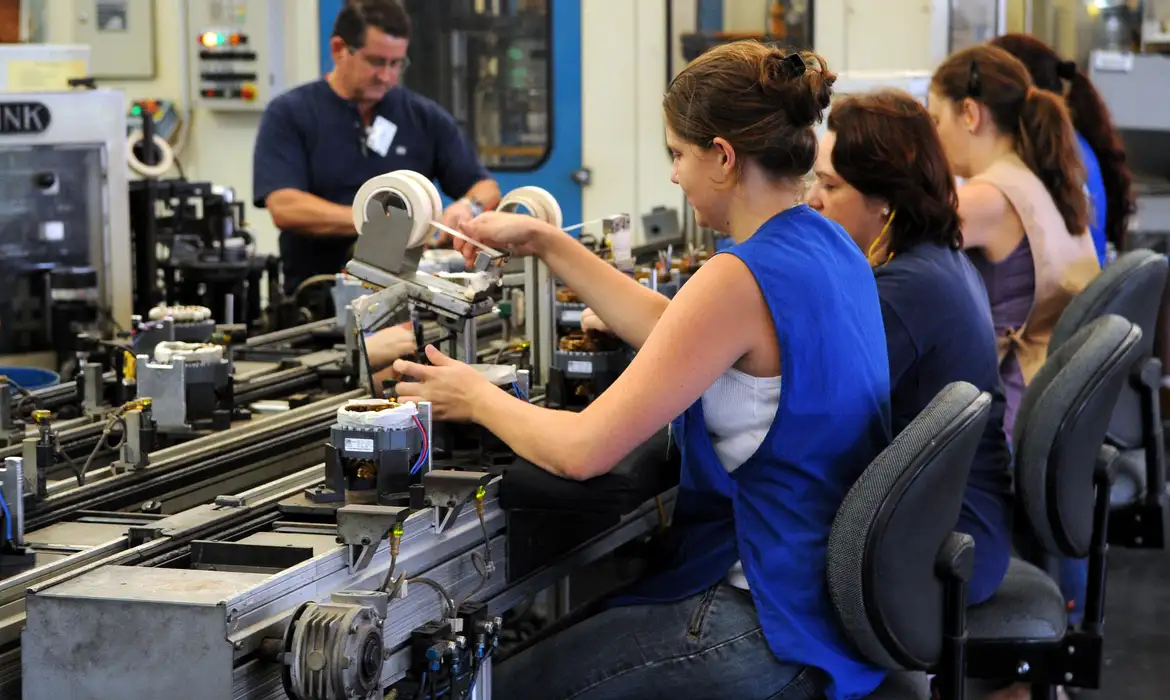 Trabalhadoras montando motores em linha automática Mulheres trabalhando em montagem de motores elétricos em linha de produção industrial