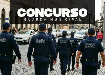 Grupo de guardas municipais uniformizados caminhando em rua de paralelepípedo com carros e pedestres ao fundo