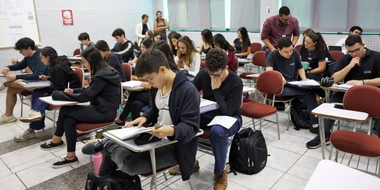 Fiscal acompanhando aplicação de prova em sala de aula com estudantes.
