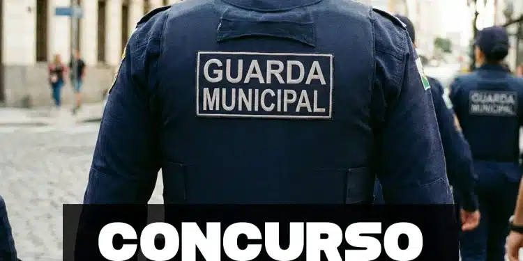 Agente da Guarda Municipal visto de costas durante patrulhamento urbano, com uniforme oficial identificado.
