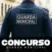 Agente da Guarda Municipal visto de costas durante patrulhamento urbano, com uniforme oficial identificado.