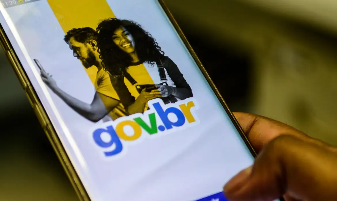 Senhora sorridente usando celular ao lado do logo gov.br, promovendo conta gov.br em 2026