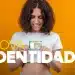 Jovem sorridente segurando nova carteira de identidade frente ao corpo, fundo laranja.