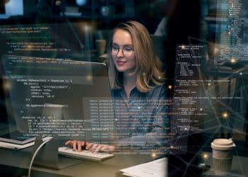 Desenvolvedora trabalhando em computador com linhas de código de programação na tela