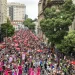 Multidão celebra Carnaval com blocos e guarda-sóis vermelhos nas ruas do Centro do Rio de Janeiro.