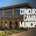 Fachada moderna da Câmara Municipal com jardim e letreiro de concurso público