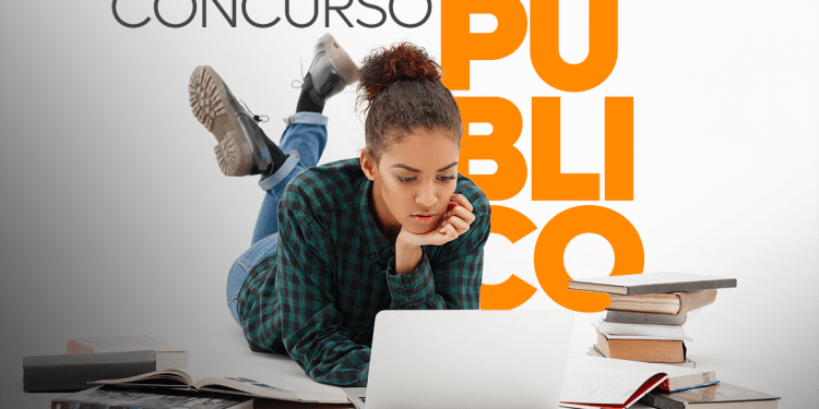 Jovem estudando em laptop com livros ao redor, referência a concurso público em 2026.