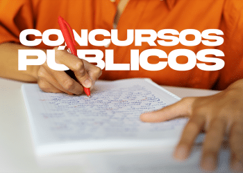 Pessoa escrevendo em caderno com caneta vermelha, foco em mão e anotações para concursos públicos