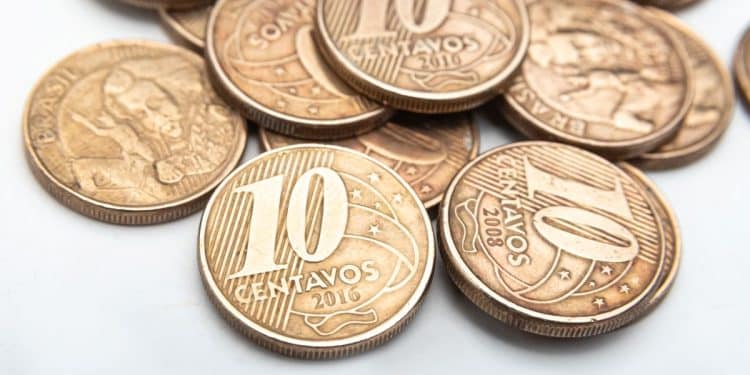 Close-up macro de uma moeda de 10 centavos de 2013, com tonalidade bronzeada, evidenciando o relevo do número 10 e as estrelas do Cruzeiro do Sul.