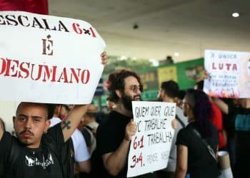 Manifestantes seguram cartazes contra a escala de trabalho 6x1 durante protesto.