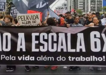 Protesto contra a escala 6x1, com manifestantes segurando faixa e cartazes pedindo mais tempo livre e qualidade de vida para os trabalhadores.