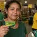 Mulher segura o Cartão Alimentação de R$ 300 dentro de um supermercado.