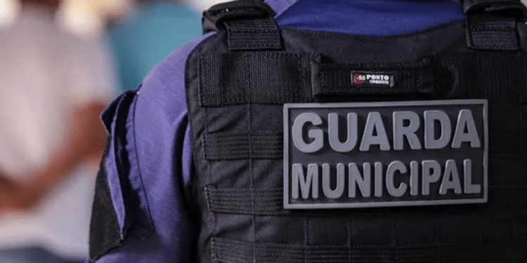 Vista traseira da Guarda Municipal usando colete à prova de balas preto com uniforme azul.