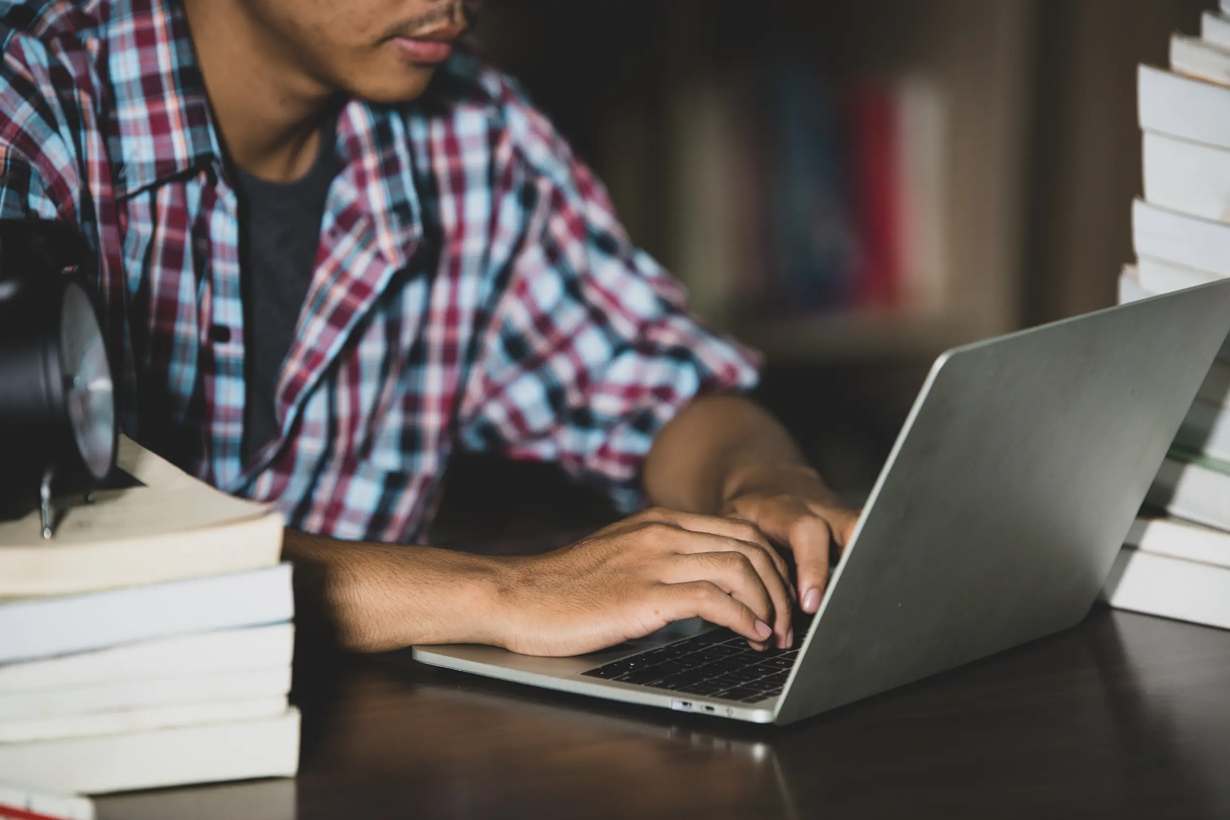 Pessoa digitando no laptop com foco em concursos públicos, representando inscrições abertas.