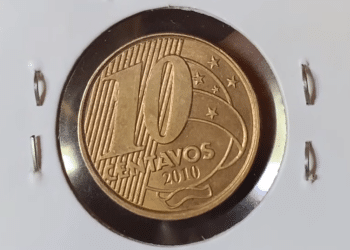 Visão frontal de uma moeda de 10 centavos de 2010, com cor bronzeada, protegida em um suporte de papel branco (coin holder). A imagem foca no numeral "10" e na data "2010" em relevo, evidenciando o brilho metálico e os detalhes da cunhagem.