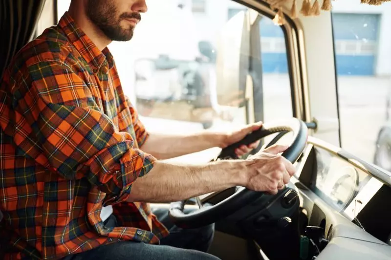 Motorista de caminhão no interior da cabine, simbolizando uma profissão simples e bem paga.