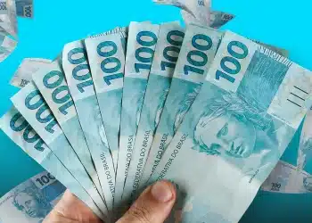 Mão segurando várias notas de 100 reais, moeda corrente no Brasil