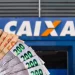 Cédulas de reais em diferentes valores em frente à fachada da Caixa Econômica Federal