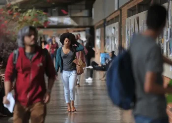 Estudante caminha por corredor universitário representando o desafio de atrair jovens para a carreira docente no Brasil.
