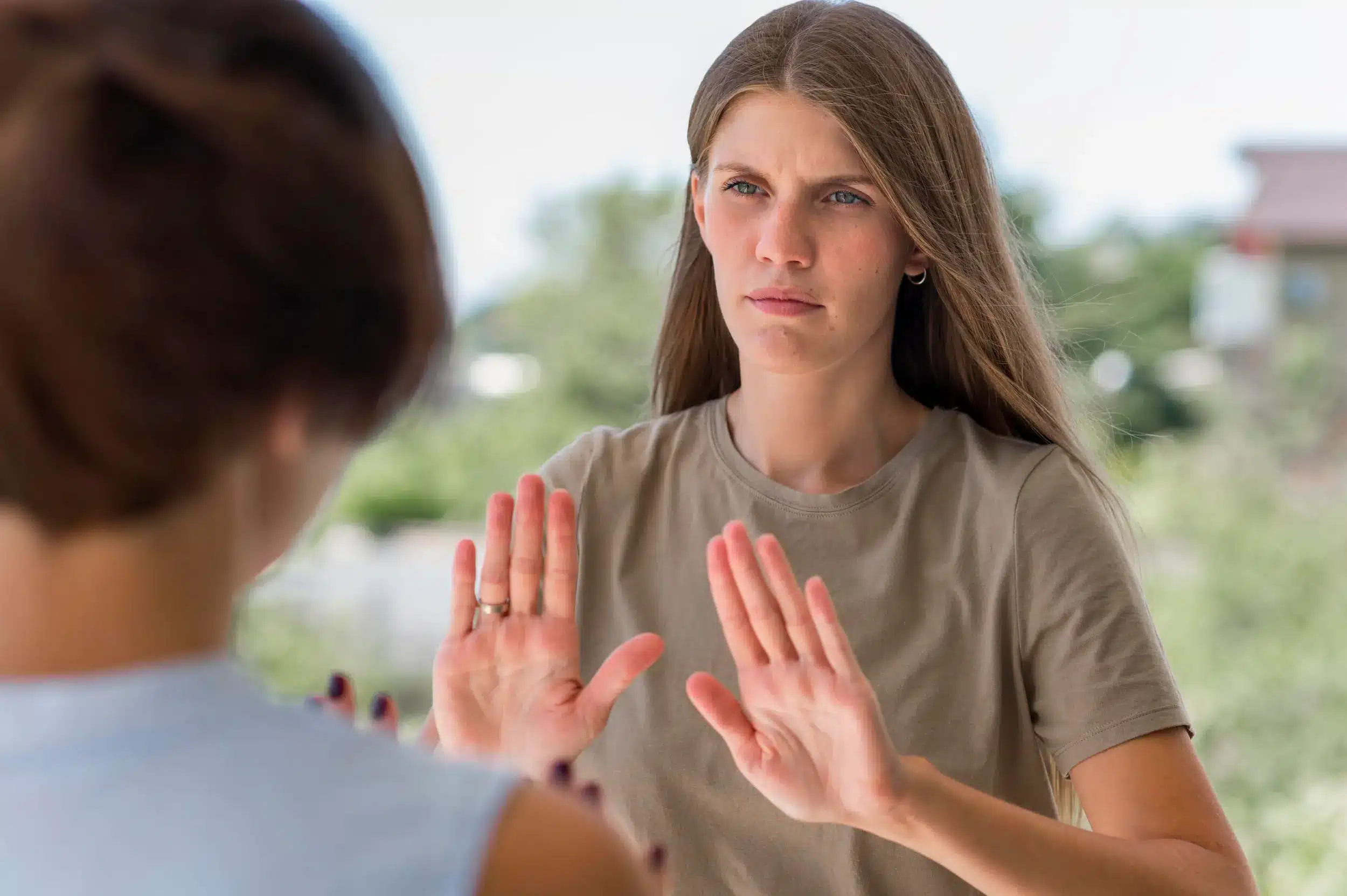 Mulher com expressão séria e mãos levantadas, simbolizando a capacidade de dizer 'não' de forma respeitosa.