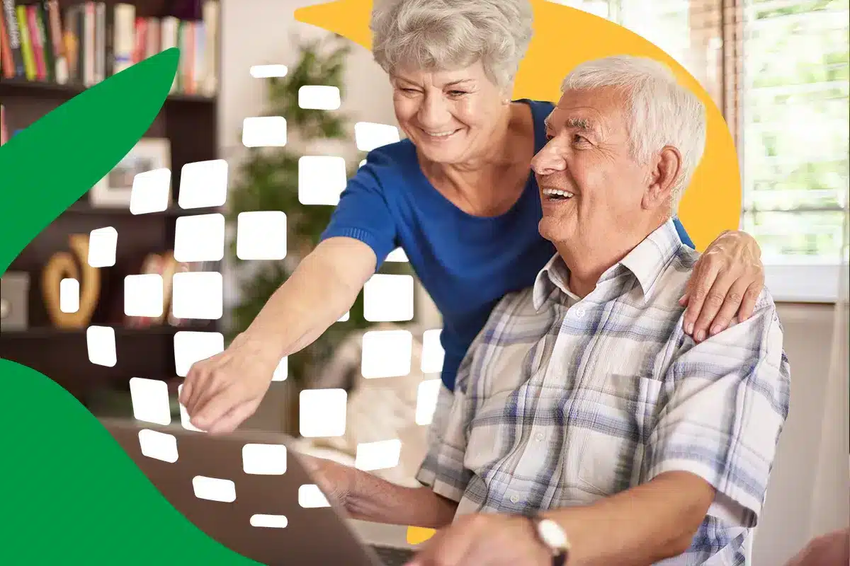 Casal de idosos sorrindo e usando computador, ilustrando a antecipação do 13º salário do INSS.