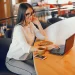 Profissional trabalhando remotamente em um café, com computador e xícara de café, representando uma profissão que pode pagar mais de R$ 10 mil por mês.