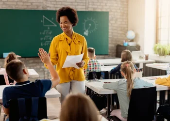 Professora interagindo com alunos em sala de aula, exemplificando o ensino nas redes estaduais.