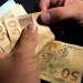 Beneficiário do INSS segurando cédulas de cinquenta reais em mãos