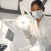 Dentista realizando atendimento clínico em consultório odontológico com equipamentos profissionais.