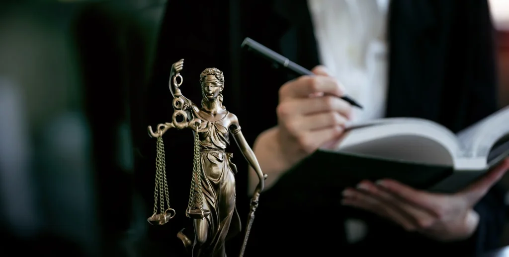 Estátua da Justiça ao lado de estudante fazendo anotações, representando a preparação para ingressar nas melhores faculdades de Direito.