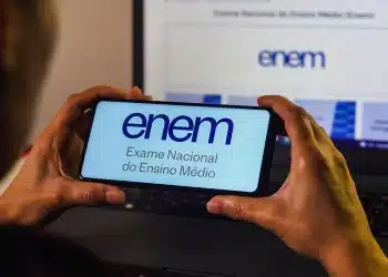 Logo do Enem 2025 exibido em um celular, com a declaração para matrícula na educação superior disponível no site.