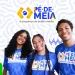 Três novos beneficiários do programa Pé-de-Meia, sorrindo e usando camisetas com o logo do programa em um fundo com formas geométricas.
