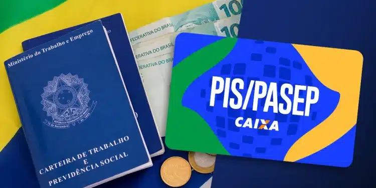 Carteira de trabalho, notas de cem reais, moedas e cartão PIS/Pasep sobre bandeira do Brasil.