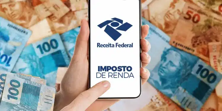 Mãos segurando celular com tela da Receita Federal e notas de real ao fundo.